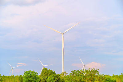 Wind turbines on landscape against sky