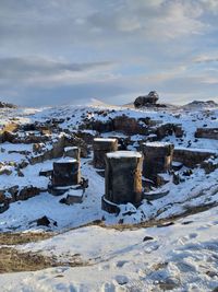 Snow covered rocks on field against sky