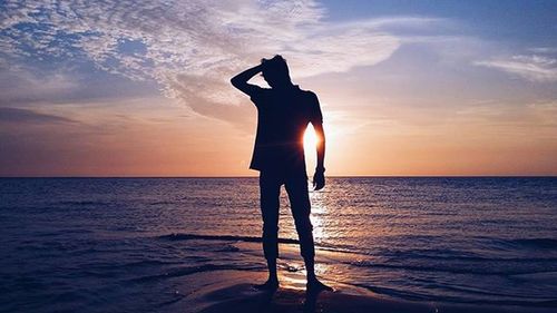 Silhouette of people on beach at sunset