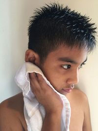 Close-up of boy cleaning face with napkin