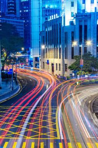 Light trails on city street by buildings at night