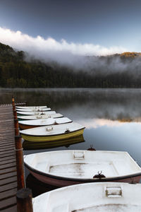 Boats moored on lake against sky