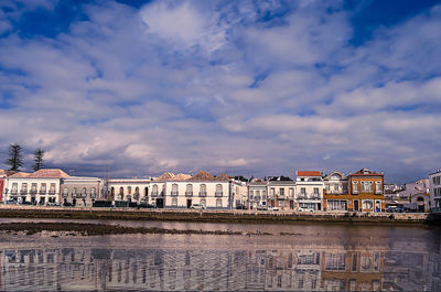 Buildings in city against cloudy sky