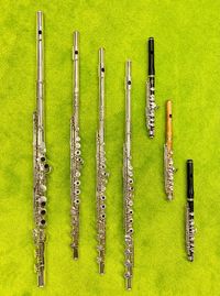 High angle view of musical equipment, alto flute, flutes and piccolos, on green surface