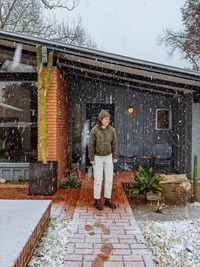 Portrait of woman standing in snow against building