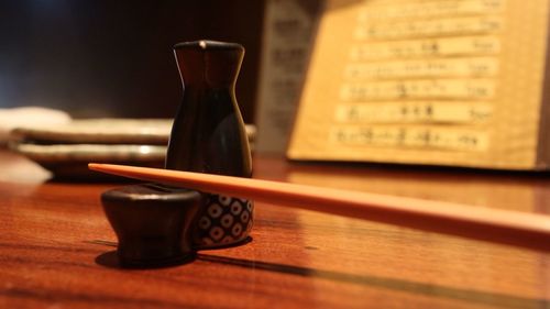 Close-up of bottle with chopsticks on table