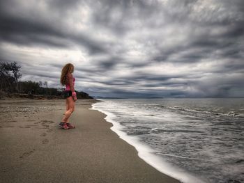 Rear view of woman on beach against sky