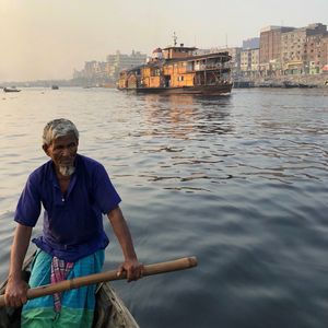 Man in boat against river buriganga 