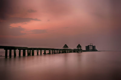 Silhouette pier over sea against sky at sunset