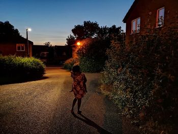 Rear view of woman walking on street amidst buildings in city