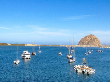 Sailboats in sea against blue sky