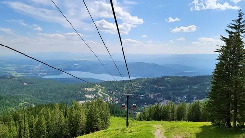 Overhead cable car on landscape against sky