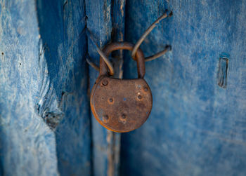 Close-up of rusty padlock hanging on wooden door