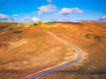 Scenic view of road amidst field against sky