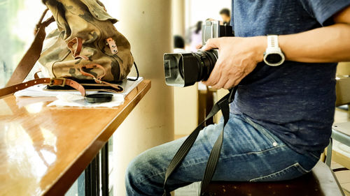 Midsection of man photographing while sitting on seat