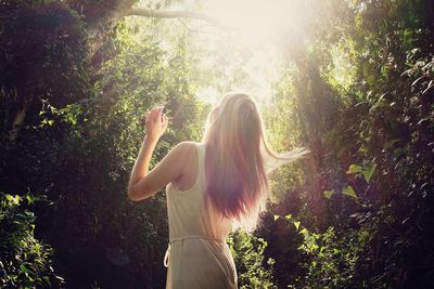 Rear view of a woman standing against trees