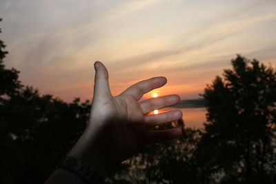 Midsection of person against sky during sunset
