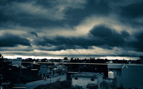 High angle view of buildings in city against storm clouds