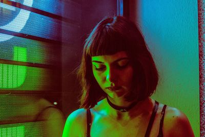 Close-up of young woman standing against wall