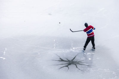 From above unrecognizable hockey player shooting puck on ice in canada