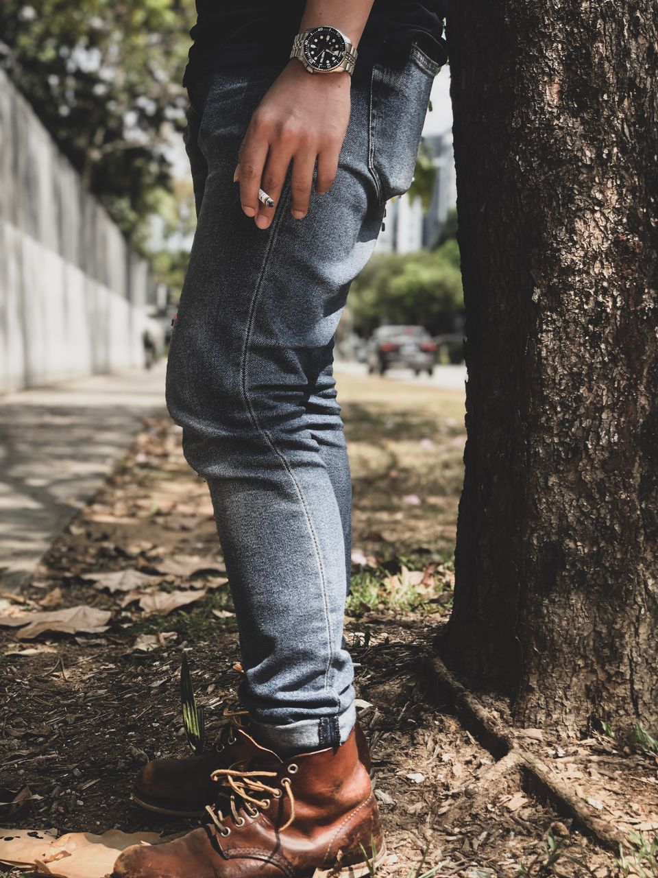 low section, one person, real people, human body part, lifestyles, body part, trunk, human leg, tree trunk, nature, tree, focus on foreground, casual clothing, jeans, leisure activity, day, standing, outdoors, shoe, hand, human limb, human foot