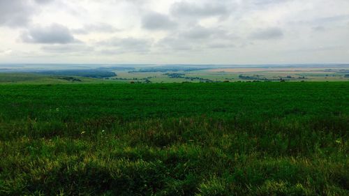 Scenic view of grassy field against cloudy sky