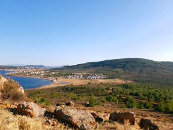 Scenic view of landscape and sea against clear blue sky