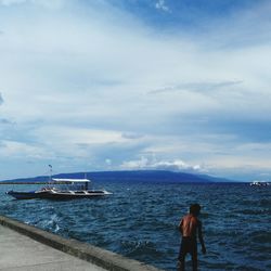 Rear view of man standing on beach against sky