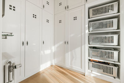 Interior of spacious store room with white built in cupboard and shelves with metal containers designed in minimal style