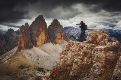 Rear view of man standing on rock against sky