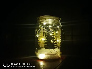 Close-up of illuminated lamp on table against black background