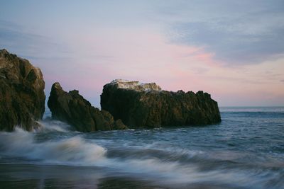 Scenic view of rocks in sea against sky during sunset