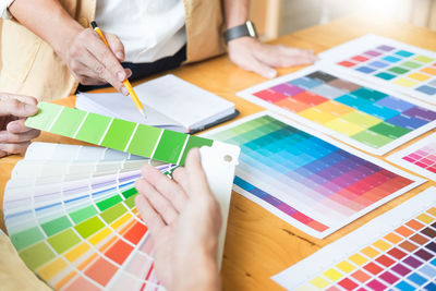 Colleagues discussing over color swatch at desk in office
