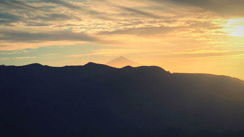 Scenic view of silhouette mountains against sky at sunset