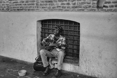 Man playing guitar against wall