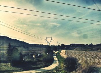 Electricity pylon against cloudy sky