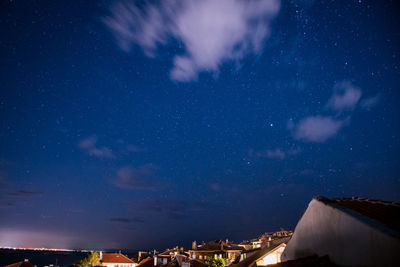 Illuminated houses in town against sky at night