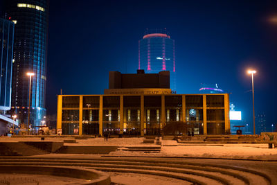 Illuminated city against clear blue sky at night