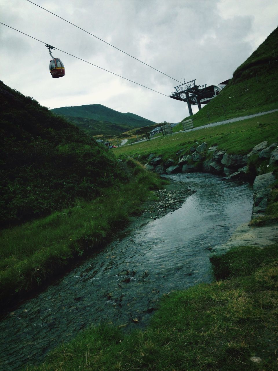 mountain, landscape, sky, electricity pylon, grass, tranquil scene, transportation, water, tranquility, connection, power line, nature, scenics, field, electricity, beauty in nature, fuel and power generation, overhead cable car, non-urban scene, power supply