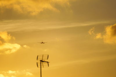 Low angle view of silhouette airplane flying against sky during sunset