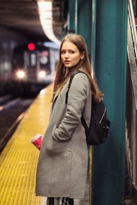 Beautiful young woman standing in illuminated city