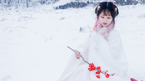 Woman holding red flowers standing on snow