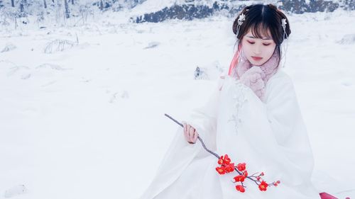 Full length of woman holding snow on field during winter