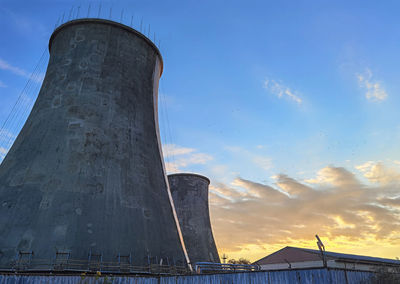 Low angle view of factory against sky during sunset