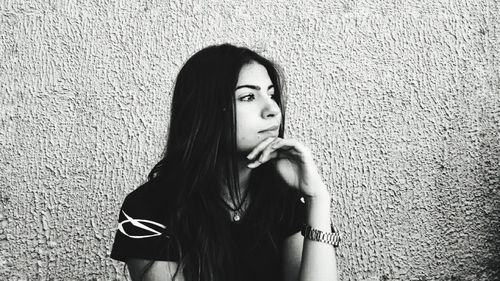 Portrait of young woman standing against wall