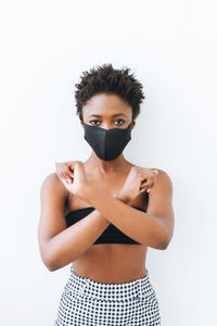 Beautiful young african american woman in black top and face mask isolated on the white background