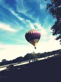 Hot air balloon flying over road against sky