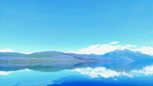 Scenic view of lake and mountains against blue sky