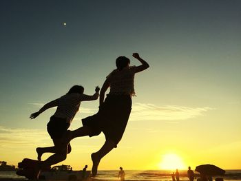 Silhouette man jumping on sea against sky during sunset