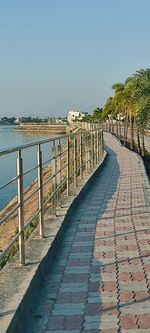 Footpath by sea against clear sky